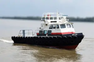 A small black and white boat from the Original Fleet with red trim moves through calm water, surrounded by rubber bumpers, under a cloudy sky.