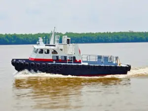 A small tugboat named "MISS EVY," part of the Original Fleet, travels on a calm river with a treeline visible in the background.