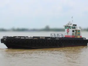 A black tugboat named "Miss Brennyn," part of the Original Fleet, floats on calm water, with tires along its sides and a white cabin featuring red accents.